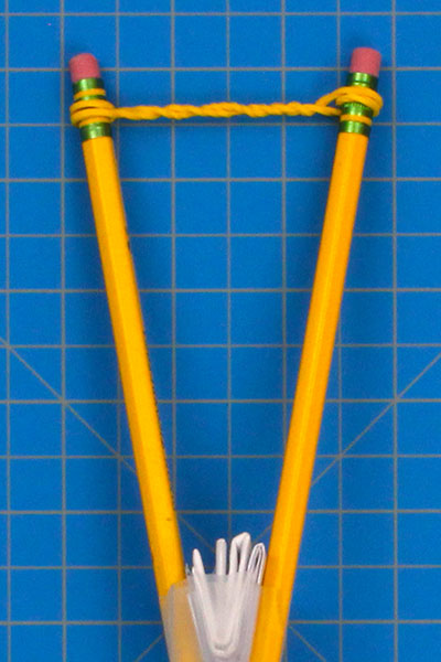 Attach a rubber band to the pencil launcher