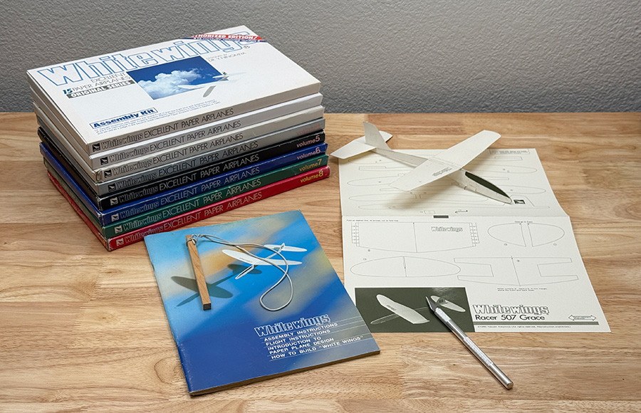 All 8 Whitewings sets stacked in a pile with an example airplane